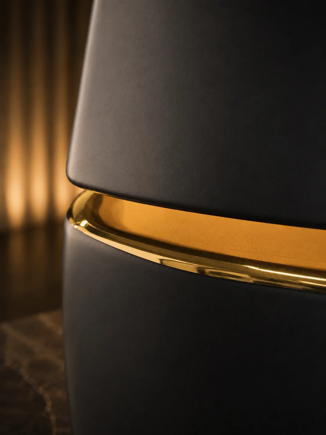 The hand-laid gold band on the edge of a matte black porcelain piece